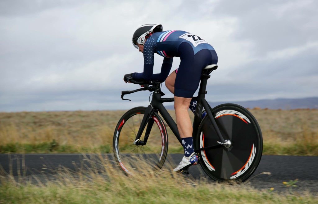 Cyclist riding a time trial bike in an aerodynamic position on an open road