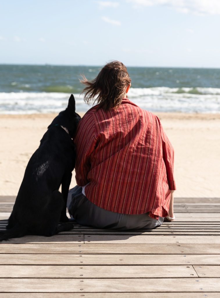 Enhance Life Psychology Albert Park, Nonie Carr Melbourne Psychologist Person sitting with a dog looking out to the ocean, reflecting attention directed to the present moment
