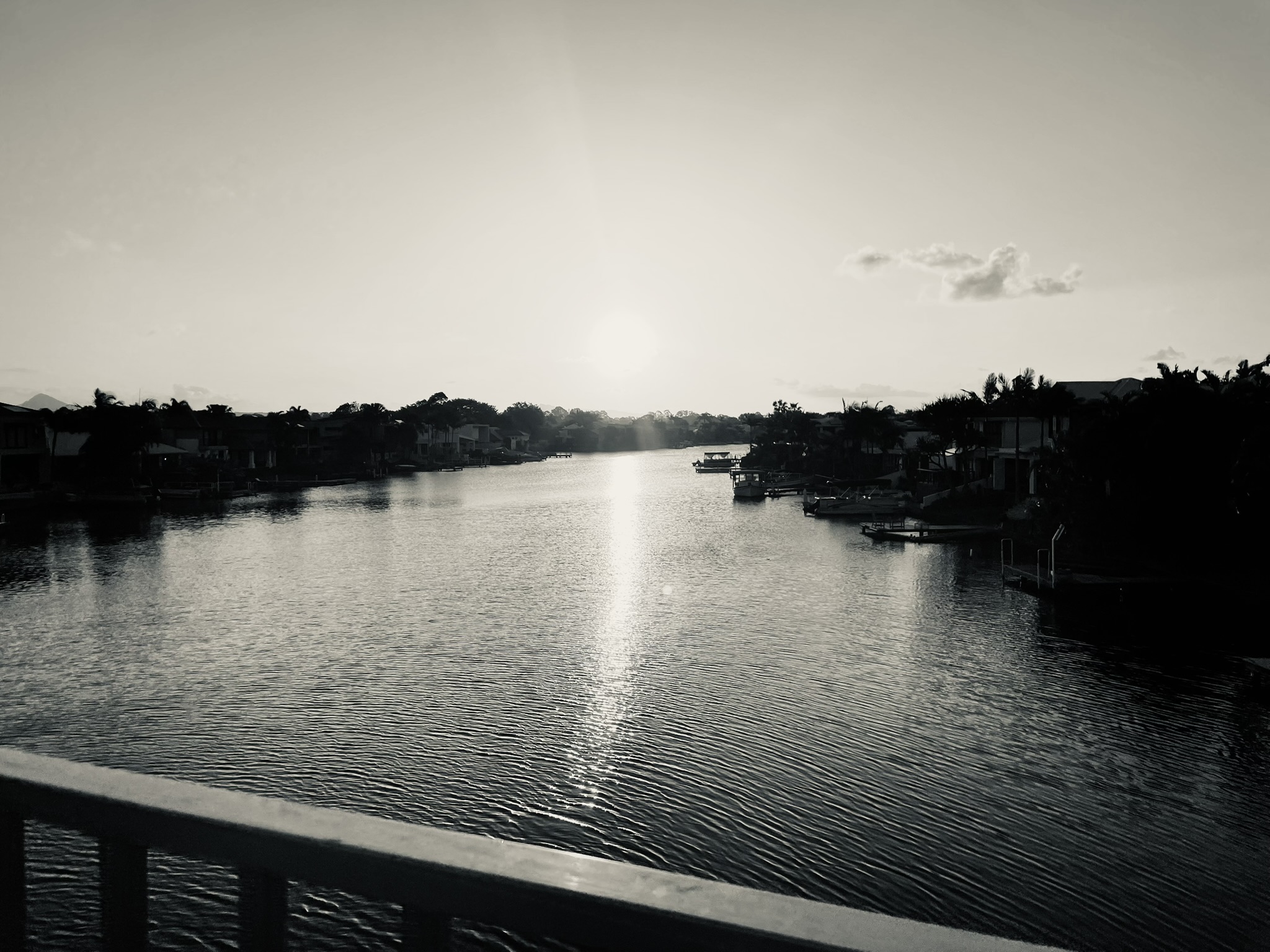 A quiet river at sunset with still water and soft clouds, creating a calm and reflective atmosphere.