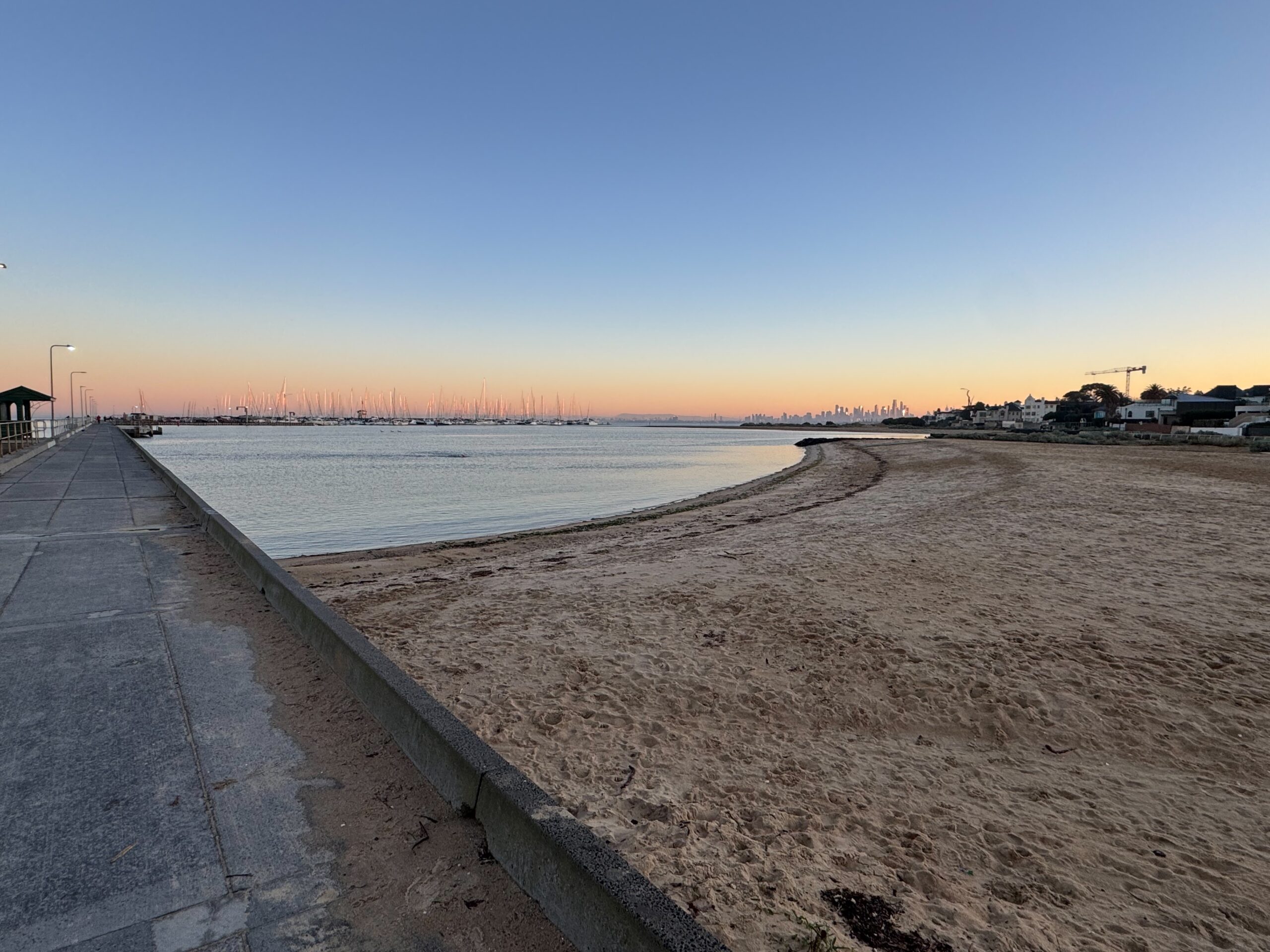 Pier beside calm water on a quiet morning under a clear sky.
