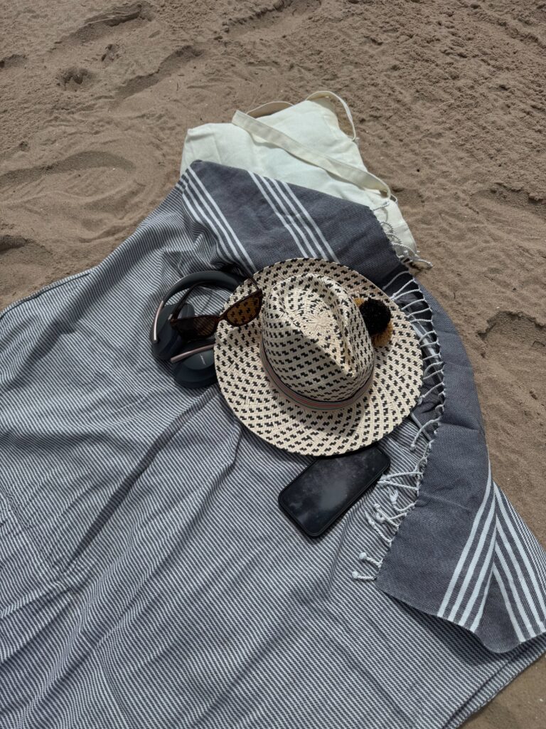Headphones and smartphone resting on a beach towel on sand