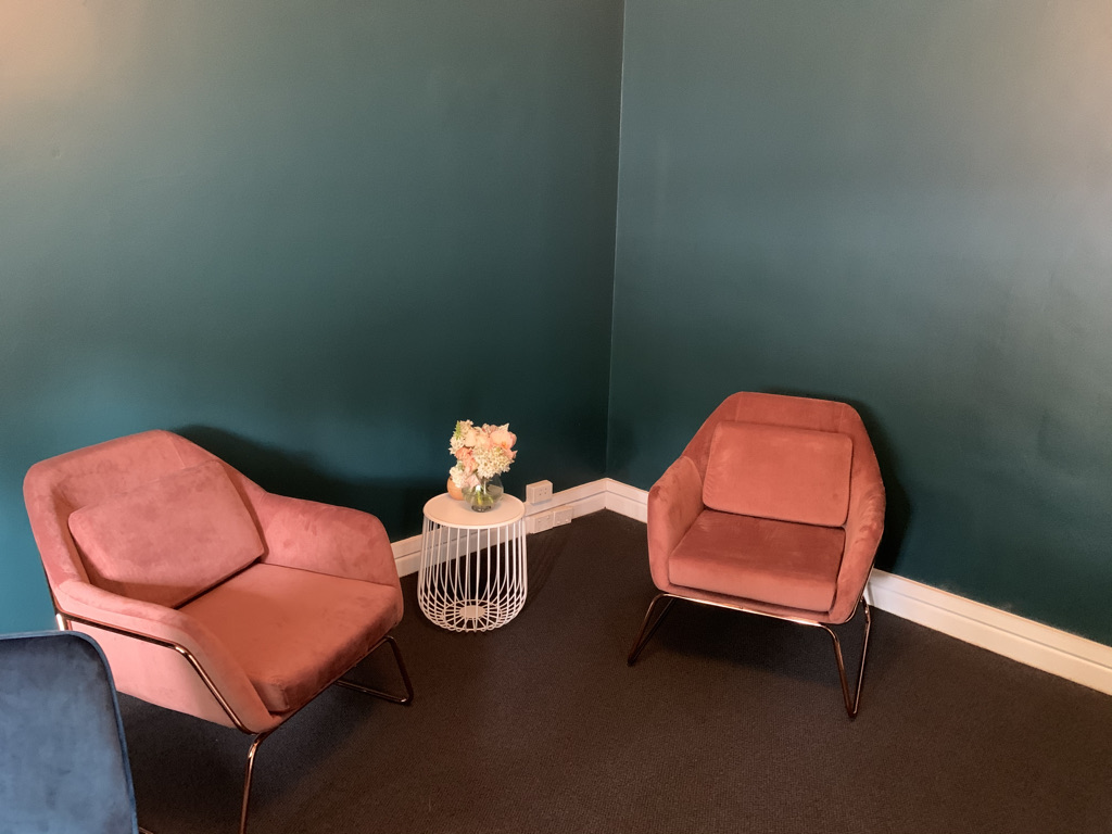 Two empty chairs facing each other in a quiet room with soft lighting