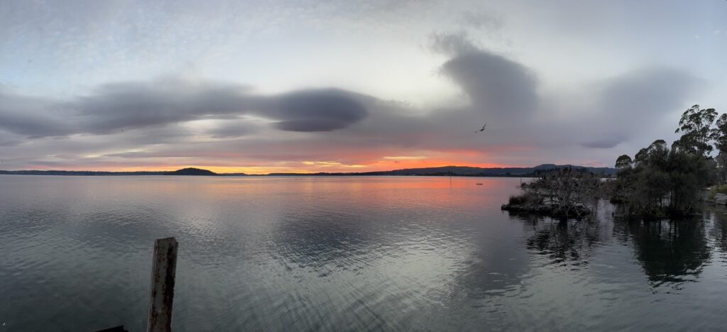 Calm water at sunset with expansive horizon, reflecting perspective and living well with uncertainty