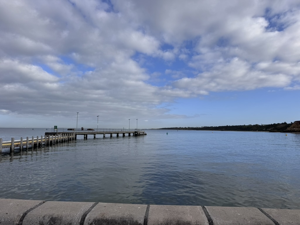 Jetty extending into calm water under a wide sky, representing perspective and performance psychology