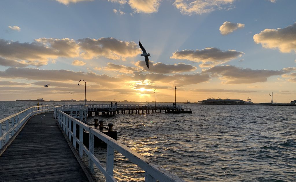 Enhance Life Psychology Albert Park, Nonie Carr Melbourne Psychologist Sunset over a pier and moving water with a bird in flight, reflecting attention and performance under pressure