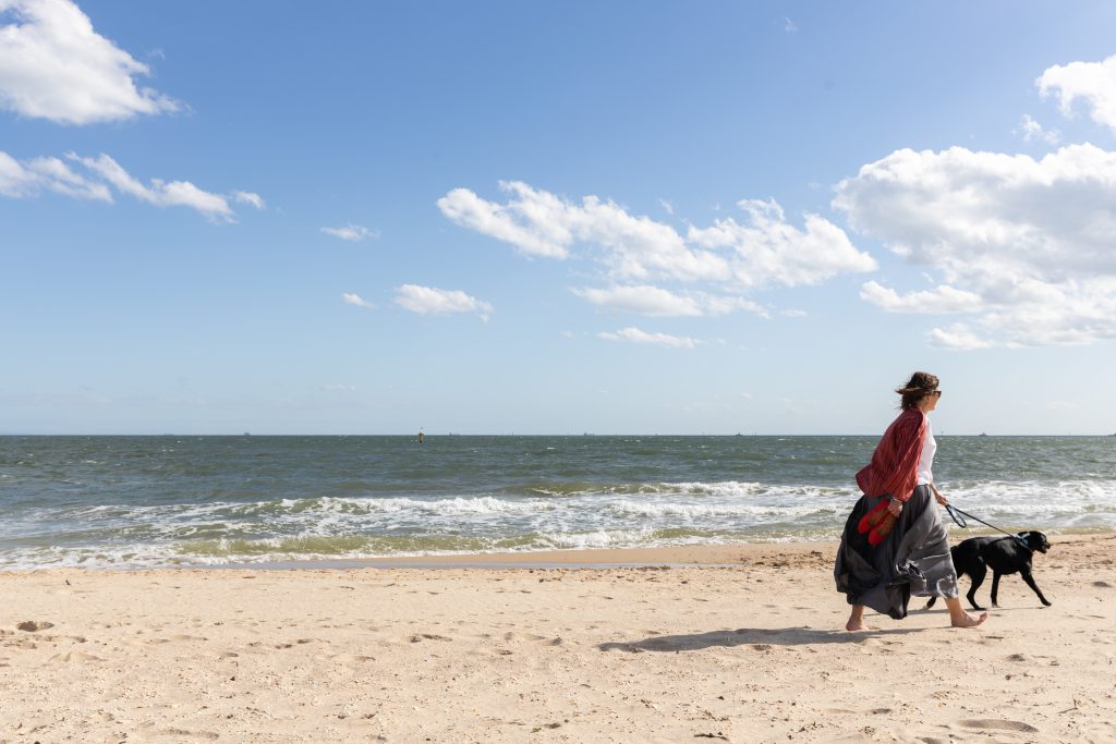 Walking barefoot along the beach with a dog beside the ocean
