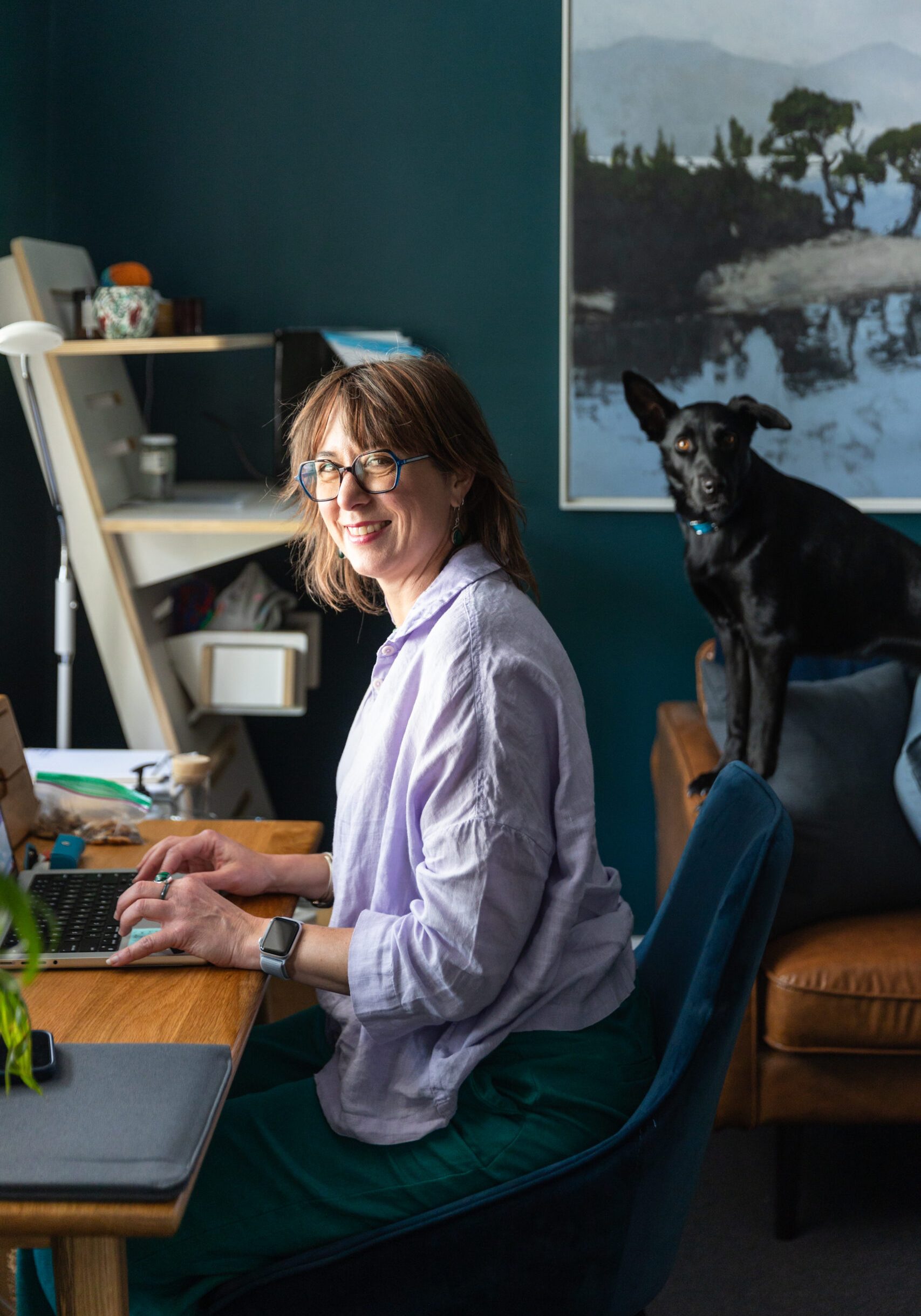 Counselling & Clinical Psychologist Nonie Carr working at her desk in her Albert Park practice, with her Kelpie Bindi nearby.