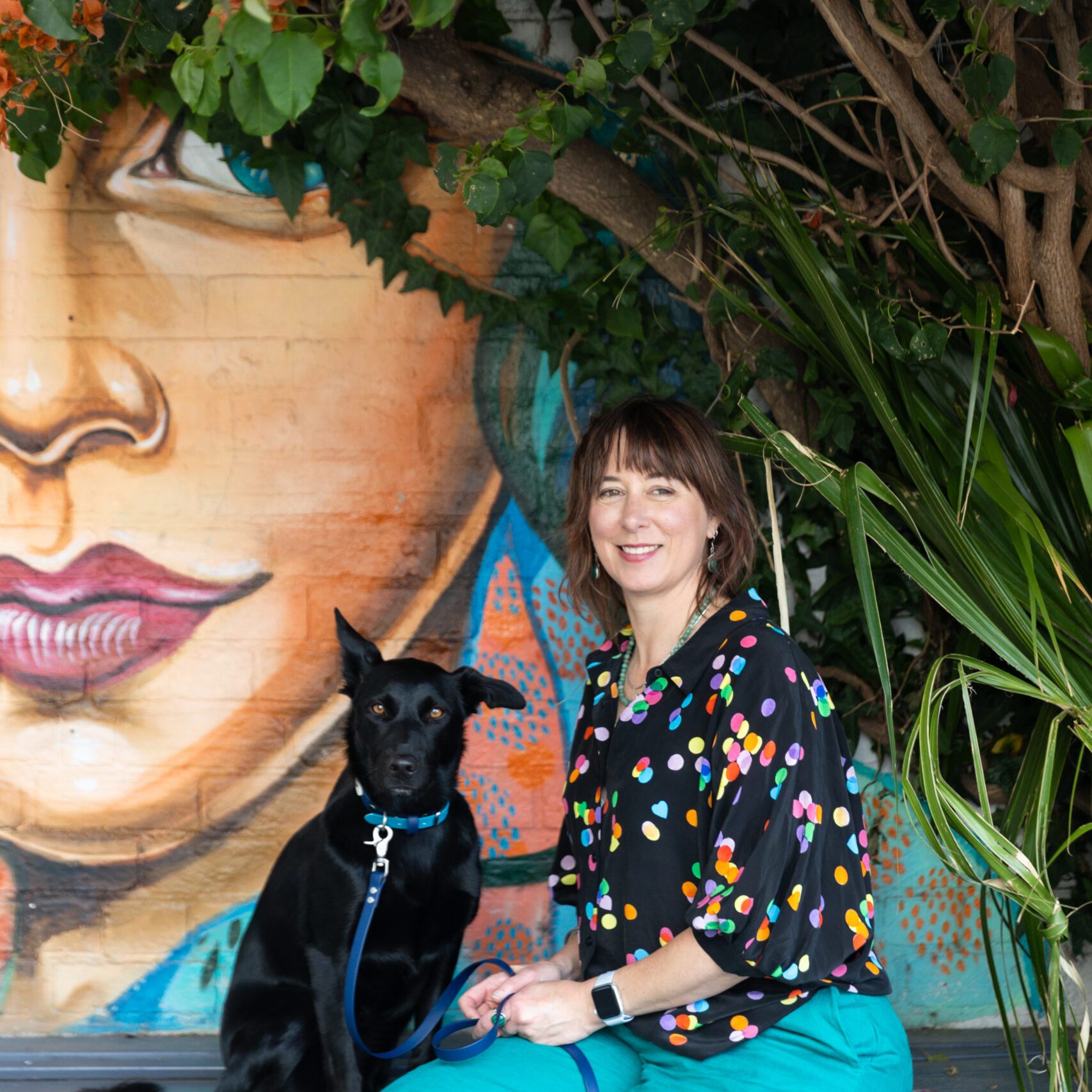 Psychologist Nonie Carr sitting with her black Kelpie, Bindi, symbolising a welcoming therapeutic approach at Enhance Life Psychology in Melbourne.