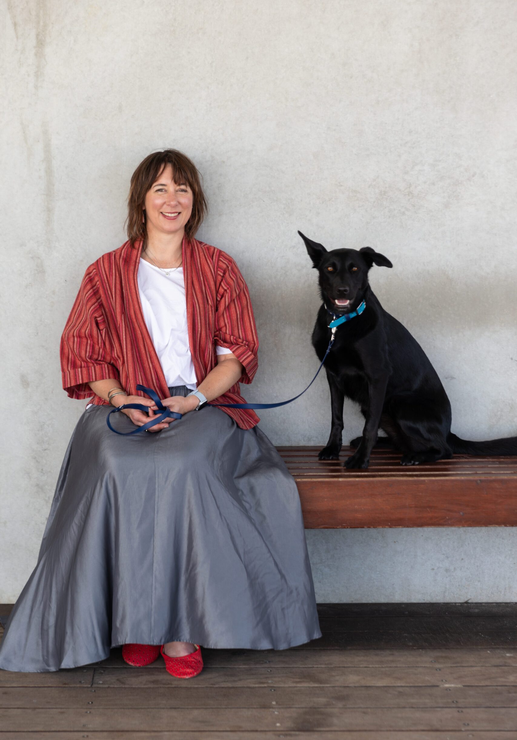 Psychologist Nonie Carr sitting with her black Kelpie, Bindi, symbolising a calm and supportive therapeutic approach at Enhance Life Psychology in Melbourne